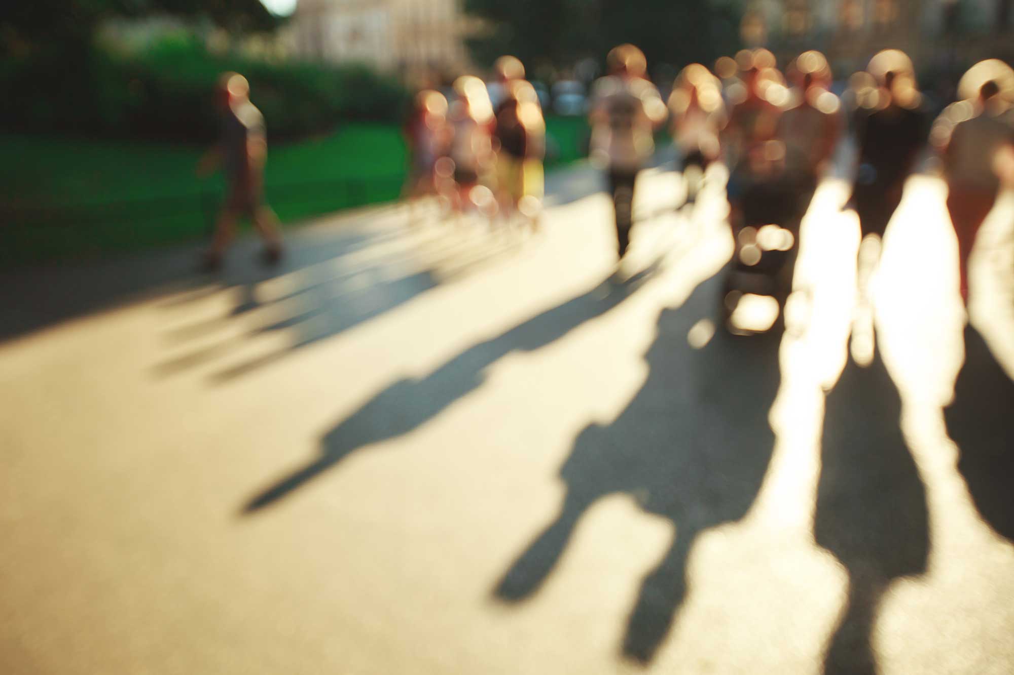 blurred shot of people walking with long shadows